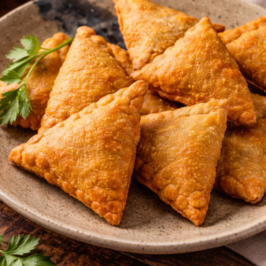 سمبوسة بيتية ذهبية مقرمشة بحشوة اللحم على طبق تقديم مرفق بصلصة الطماطم الحارة